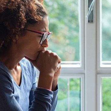 Portrait of pensive black woman standing beside window