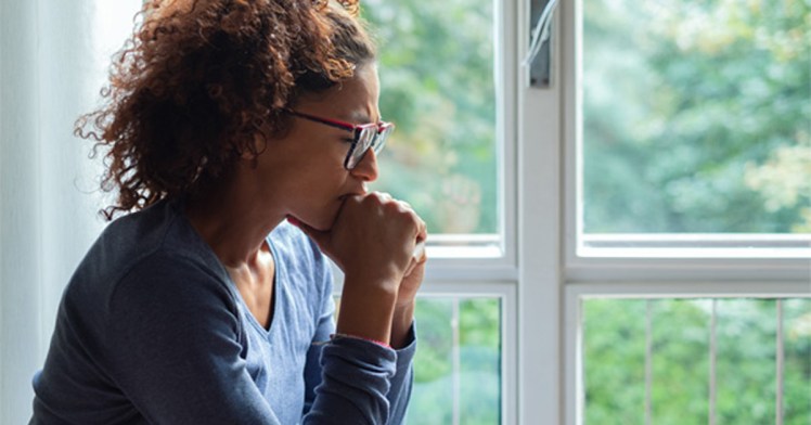 Portrait of pensive black woman standing beside window